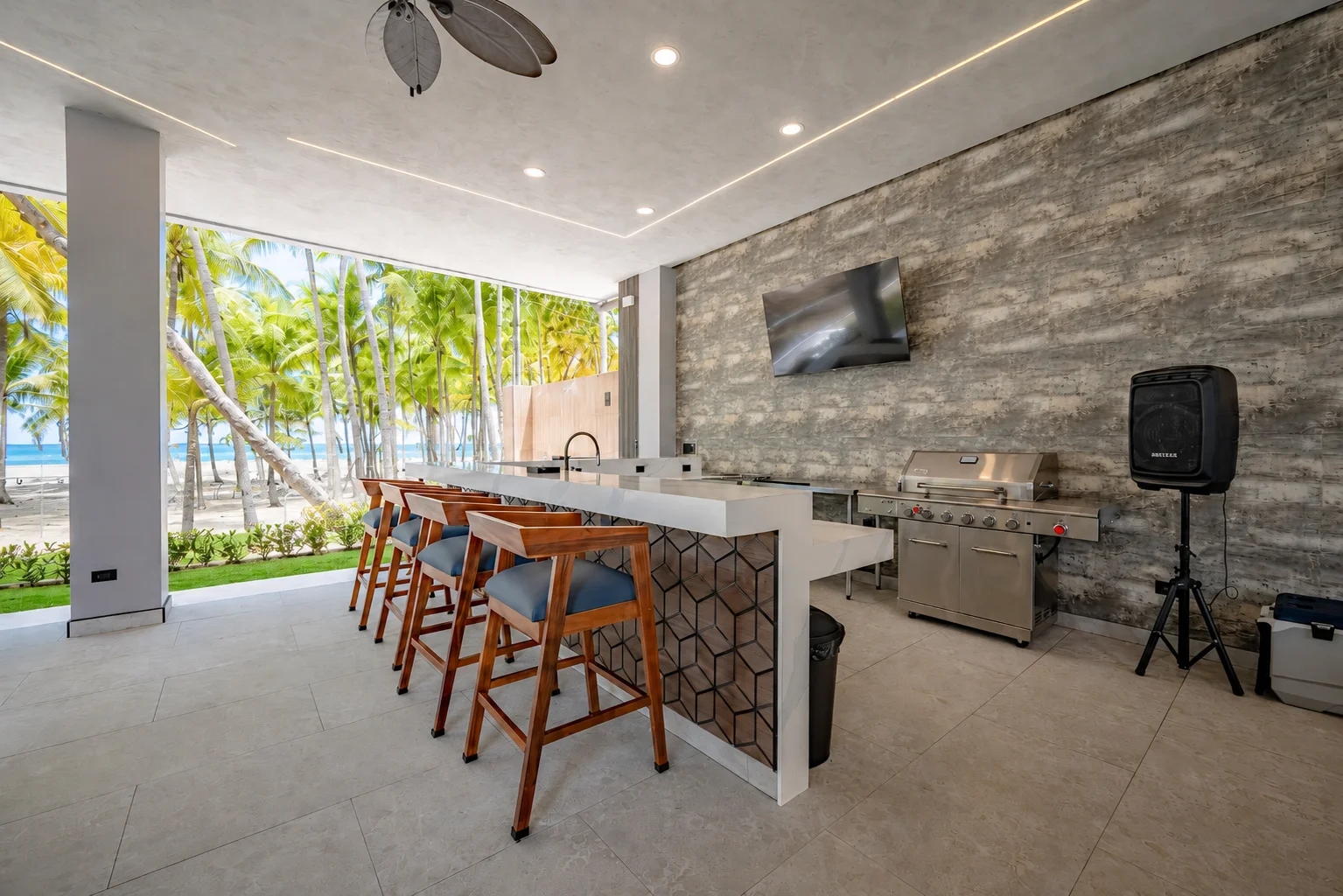 Covered beachfront bar with stools looking out to the palm grove and the Pacific